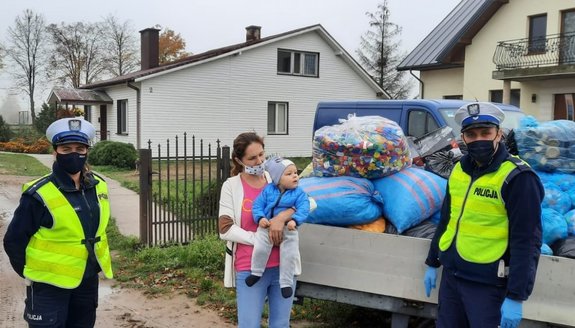 Umundurowani policjanci stojący z zebranymi nakrętkami