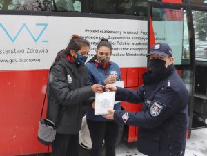 Policjanci oraz siatkarki stojące obok autobusu