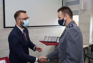 Umundurowany policjant oraz cywil stojący w maseczkach