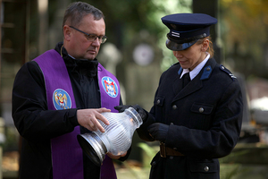 policjantka z księdzem zapala znicz