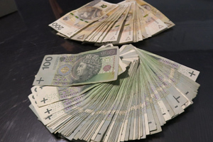 Banknoty o nominałach 100 i 200 PLN leżące na blacie.