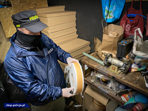 policjant CBŚP trzyma i pokazuje materiały