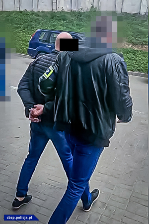 policjanci CBŚP prowadzą osobę zatrzymaną