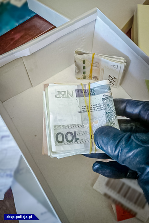 policjant trzyma w ręce pieniądze