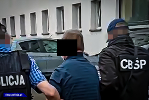 policjanci prowadzą osobę zatrzymaną