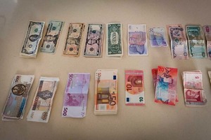 Dolary, euro, złotówki oraz inne banknoty o różnych nominałach leżące na blacie stołu.