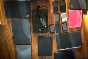 Laptopy, tablety i telefony komórkowe leżące na blacie stołu.