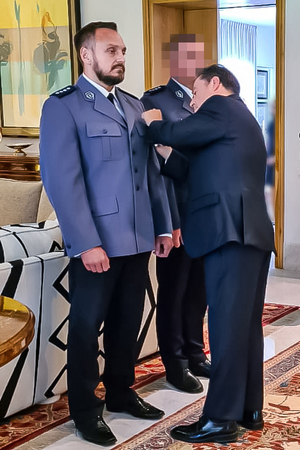 osoba przyczepia medal na mundur policjanta