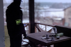 policjant CBŚP stoi na balkonie obok stołu na którym znajduje się amunicja.