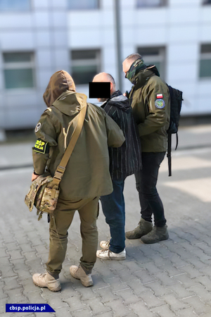 policjanci CBŚP prowadzą osobę zatrzymaną