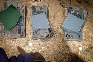 Banknoty o nominałach 100 oraz 500 PLN leżące na stole.