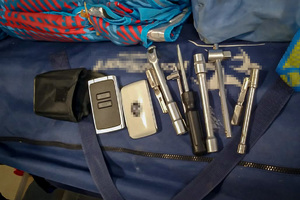 Różnego rodzaju narzędzia ręczne i elektroniczne leżące na torbie podróżnej.