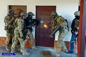 Policyjni kontrterroryści wchodzący siłowo do pomieszczenia.