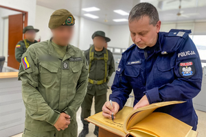 Zastępca Komendanta Głównego Policji dokonuje wpisu do księgi pamiątkowej, obok policjanci kolumbijscy.