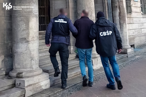 Funkcjonariusze CBŚP oraz Służby Celno-Skarbowej wprowadzają zatrzymanego do budynku.