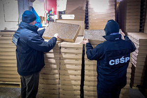 Funkcjonariusze CBŚP i Straży Granicznej sprawdzają kartony wypełnione papierosami.