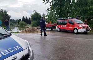 Policjanci i strażacy zabezpieczają zalaną drogę