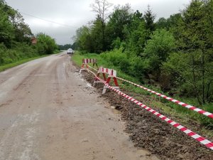 droga zanieczyszczona błotem, osunięty teren oznaczony taśmą, w tle policyjny radiowóz