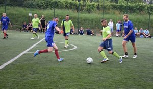 Fotografia kolorowa na której widać zawodników sportowych którzy rozgrywają mecz na boisku.