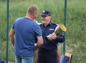 Fotografia kolorowa przedstawiająca Komendanta Powiatowego Policji w Przeworsku wręczającego puchar zawodnikowi.