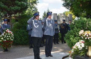 Fotografia kolorowa przedstawiająca dwóch policjantów oddających honor gen. Markowi Papale w  21. rocznicę jego śmierci.