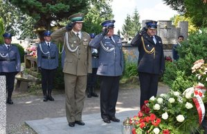 Fotografia kolorowa na której widać funkcjonariusza SG, policjanta i strażaka. Osoby te oddają hołd zmarłemu gen. Markowi Papale.