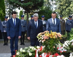 Fotografia kolorowa na której przed grobem gen. Marka Papały stoi trzech mężczyzn. Mężczyźni oddaję hołd zmarłemu.