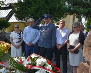 Fotografia kolorowa na której widać osoby zgromadzone przy nagrobku zmarłego gen. Marka Papały. Wśród tych osób jest umundurowany policjant który oddaje hołd zmarłemu.