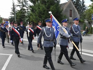 Kolorowa fotografia. Poczet sztandarowy leżajskiej Policji maszeruje ulicami miasta.