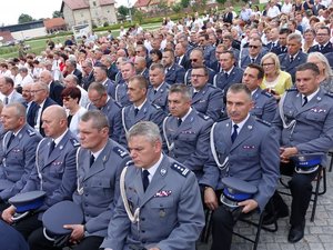 Kolorowa fotografia. Kierownictwo powiatowych jednostek Policji. Policjanci w rzędach siedzą na przygotowanych krzesłach wśród pozostałych wiernych.