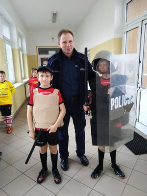 Policja stoi z dziećmi ubranymi w kamizelki taktyczne