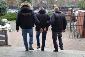 Policjanci prowadzą jednego z zatrzymanych