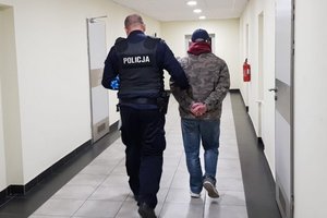 Policjanci prowadzą jednego z zatrzymanych