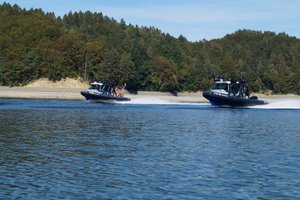 Dwie policyjne łodzie z funkcjonariuszami na pokładzie, pływające po Jeziorze Solińskim
