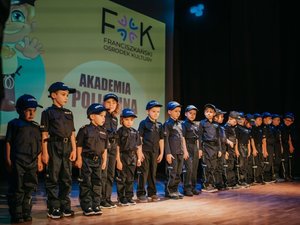 Kolorowa fotografia. na scenie stoją w rzędzie dzieci ubrane w policyjne mundury.