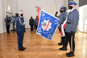 Po lewej inspektor Dariusz Matusiak, który wita się ze sztandarem Komendy Wojewódzkiej Policji w Rzeszowie. Po prawej poczet sztandarowy.