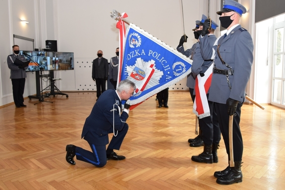 Po lewej inspektor Dariusz Matusiak, który klęka przed sztandarem Komendy Wojewódzkiej Policji w Rzeszowie. Po prawej poczet sztandarowy.