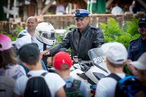 Policjanci podczas spotkania z dziećmi w Polańczyku. Na zdjęciu policjant ruchu drogowego na motocyklu w towarzystwie dzieci