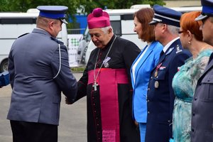 Policjant wręcza odznaczenie ks. bp Edwardowi Białogłowskiemu.