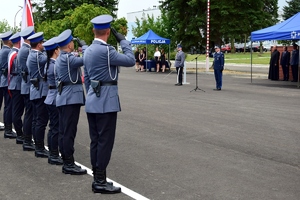 Po lewej stronie poczet sztandarowy i flagowy. Po prawej Komendant Wojewódzki Policji w Rzeszowie (przy mikrofonie) wita się z policjantami.