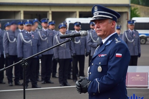 Po prawej na pierwszym planie Komendant Wojewódzki Policji w Rzeszowie przy mikrofonie. W tle policjanci na placu apelowym.