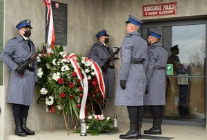 policjanci przy tablicy pamiątkowej składają znicze