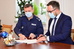 Zastępca Komendanta Wojewódzkiego Policji w Rzeszowie przy stole (po lewej) podpisuje dokumenty wraz z Wykonawcą (po prawej).