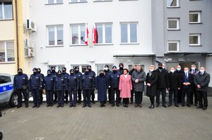 wspólne zdjęcie na tle komisariatu, od lewej nowy oznakowany radiowóz, pododdział policji, z prawej komendanci oraz zaproszeni goście, posłowie, parlamentarzyści, samorządowcy