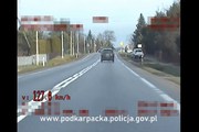 Zdjęcie z policyjnego wideorejestratora, wykonane w ciągu dnia. Na środku widoczny ciemny samochód jadący prostym odcinkiem drogi. W lewym dolnym rogu czerwony napis 127.0 km/h.
