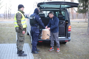 Policjant i strażnik graniczny przekazujący koce.