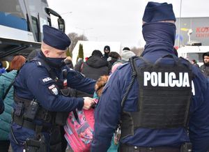 Policjant pomaga dziecku założyć plecak