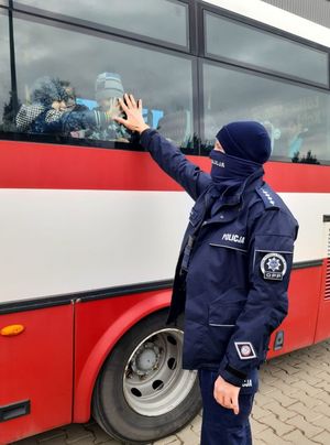 Policjant przybija dzieciom piątkę przez szybę autokaru