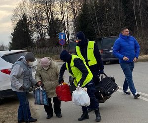 Policjanci pomagają starszym osobom przenieść ich bagaże