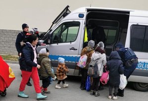 Policjanci pomagający wsiąść dzieciom do radiowozu